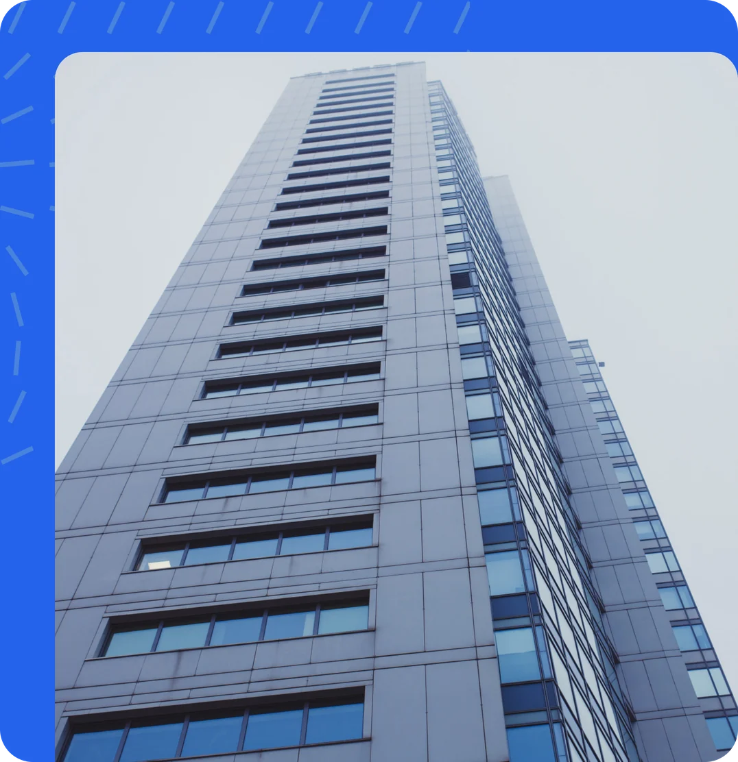 A glass tower block seen from below, framed in AssetCrate blue