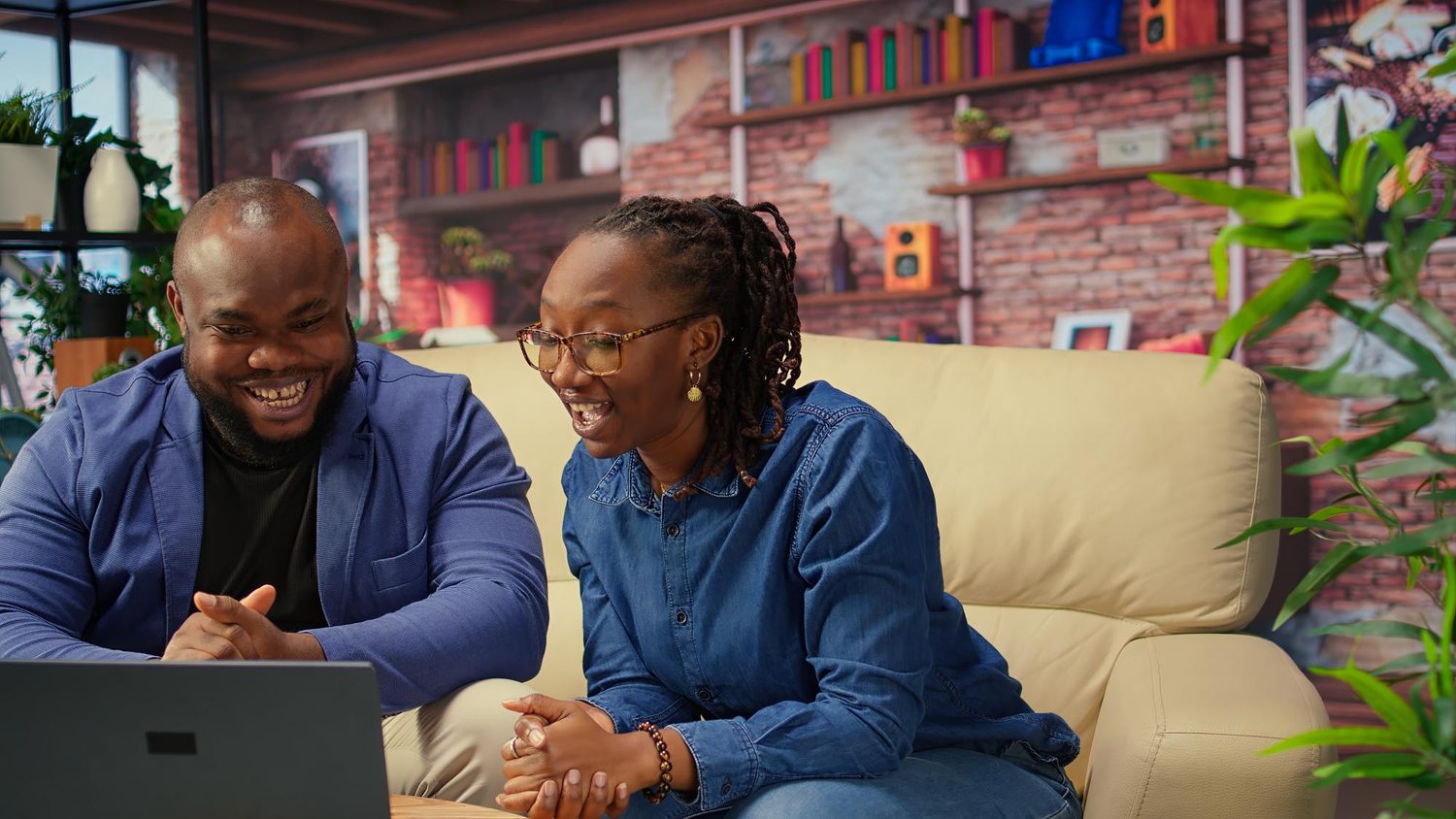Two colleagues smiling at a laptop in a bright office
