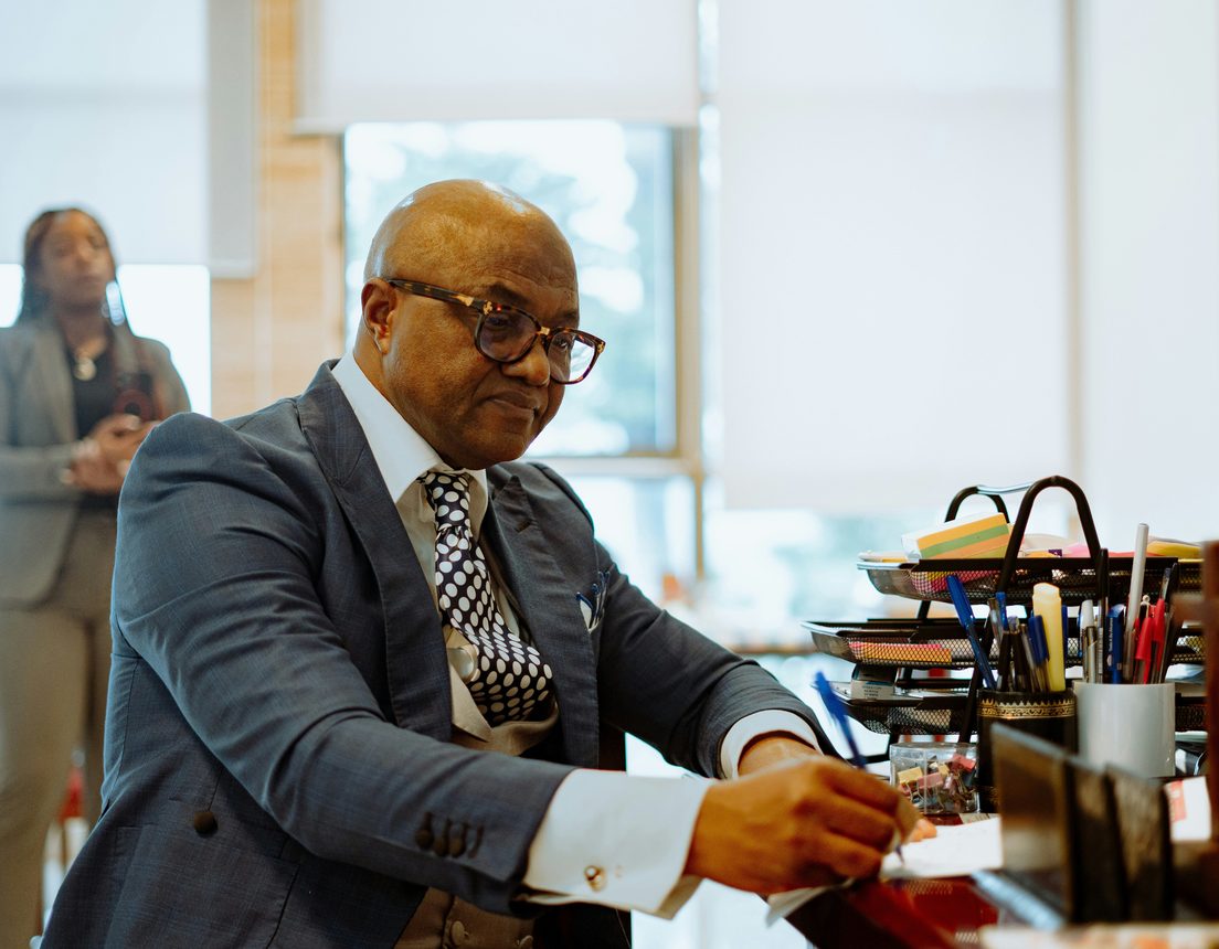 An executive in glasses signing documents at his desk