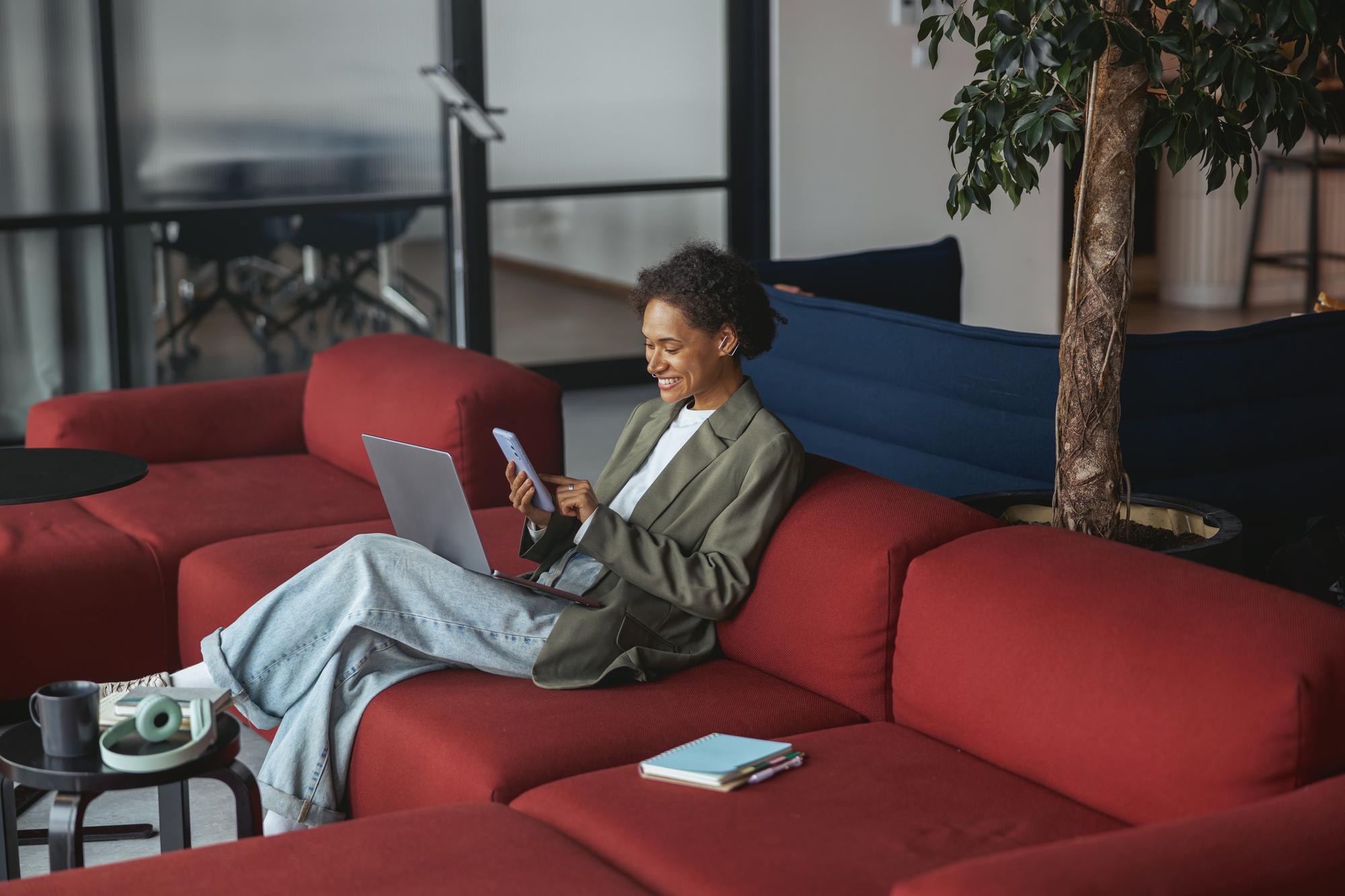 An investor smiling at her phone with a laptop on her lap