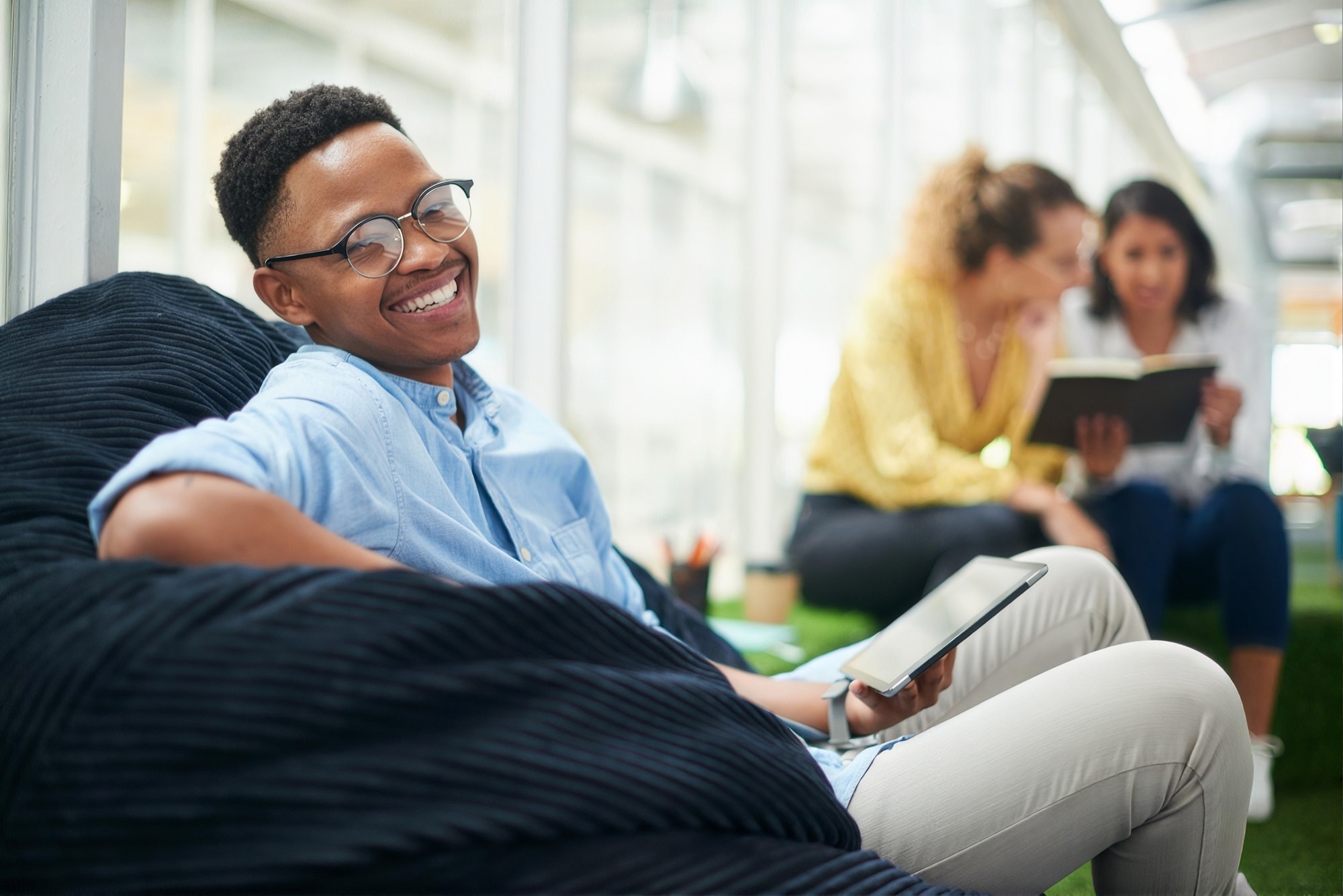 A smiling investor in glasses relaxing with a tablet